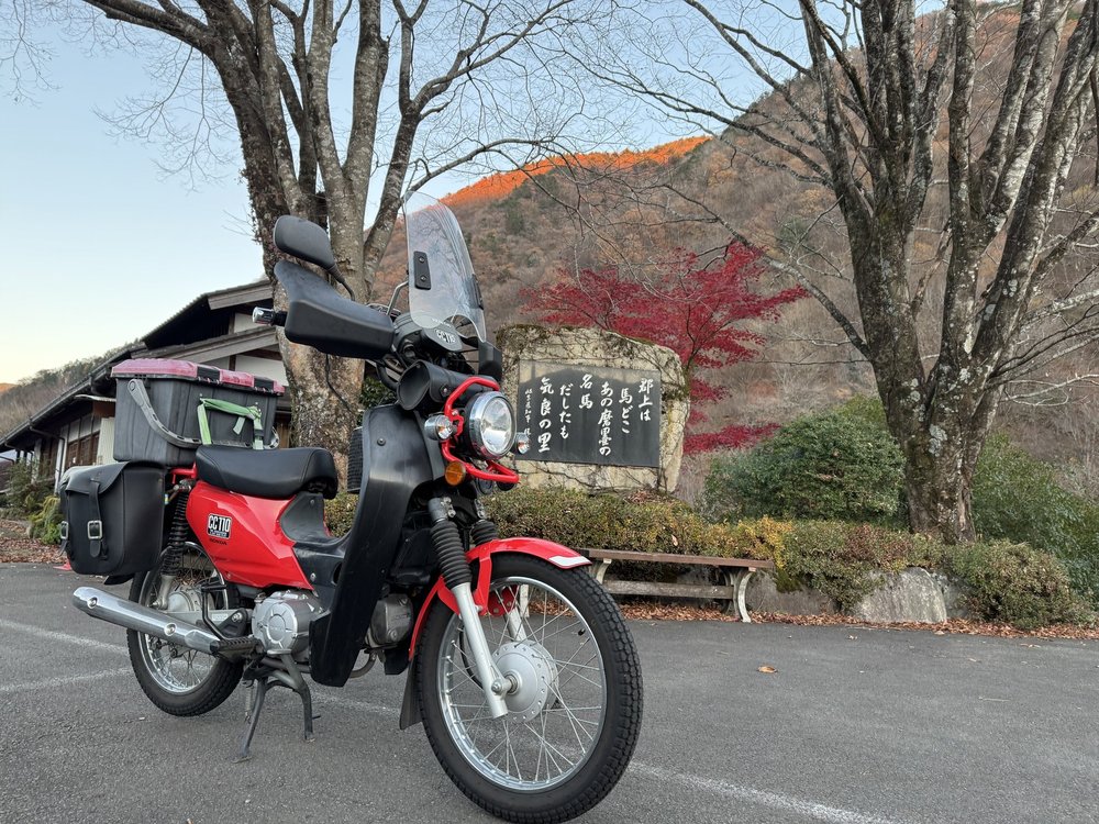紅葉に囲まれたクロスカブ110と石碑 道の駅明宝の秋