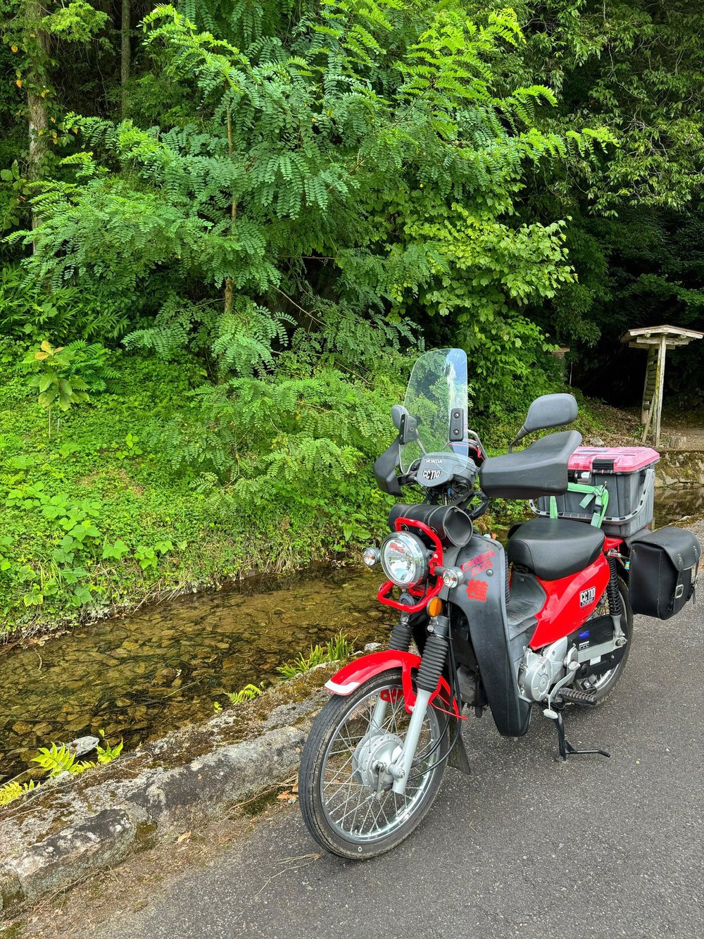 小川と新緑の中に停めたクロスカブ110
